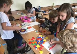 Uczniowie wybierają wzory do układania wzoru z kolorowych figur.