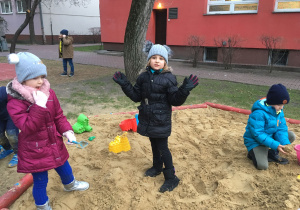 Uczniowie bawią się w piaskownicy.