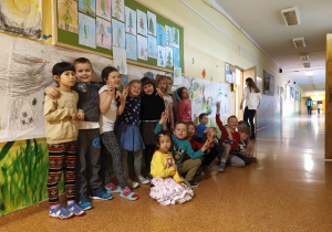 Grupowe zdjęcie po zakończeniu zajęć. W tle - praca plastyczna..