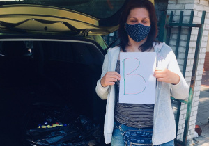 Mieszkanka Powiśla trzyma w ręku kartkę z literą "B".