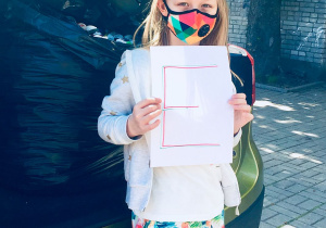 Uczennica naszej szkoły trzyma w ręku kartkę z literą "E".