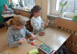 Uczennice nawlekają koraliki na drut miedziany.