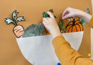 Uczeń wkłada wycięta marchewkę do misy przyczepionej do tablicy.