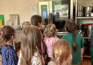 Uczniowie przyglądają się jak pieką się ich wyroby cukiernicze.