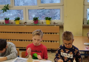 Dzieci z klasy trzeciej podczas malowania glinianych figurek.