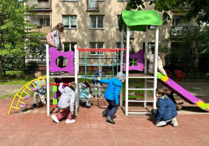 Dzieci szukają zagadek na zabawce ogrodowej.