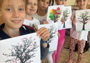 Dzieci z pracami plastycznymi - drzewa w kropki.