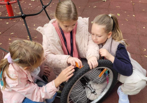 Nina, Myroslava i Sofiia zapoznają się z budową koła od roweru i sprawdzają, czy sprawdzają jest sprawne.