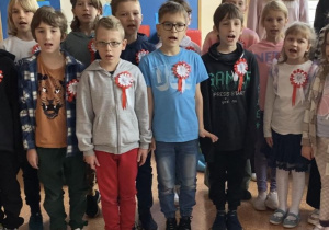 Uczniowie z kals 1-3 stoją na korytarzu i śpiewają hymn Polski.