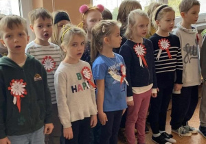 Uczniowie z kals 1-3 stoją na korytarzu i śpiewają hymn Polski.