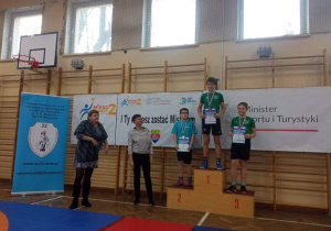 Adam z klasy 6a stoi na podium, na drugim miejscu, podczas dekoracji medalami.