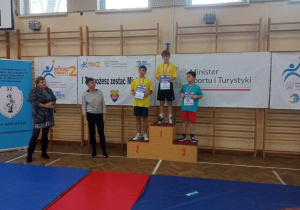 Karol z 4a stoi na podium, na trzecim miejscu, podczas dekoracji medalami.