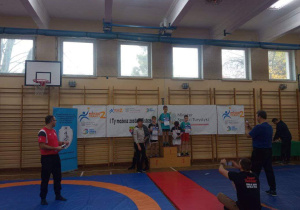 Chłopcy stoją stoi na podium, na pierwszym i trzecim miejscu, podczas dekoracji medalami.