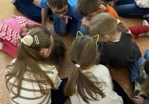 Uczniowie dzielą sie na grupy na korytarzu szkolnym.