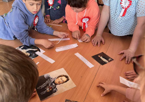 Grupa uczniów próbuje rozwiązać zadanie - rozpoznawanie polskich zabytków, pieśni i portretów sławnych Polaków.