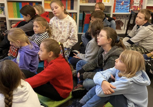 Uczniowie siedzą w księgarni i słuchają o patriotyźmie.