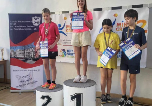 Uczniowie biorący udział w mistrzostwach stoja na podium podczas dekoracji medalami.