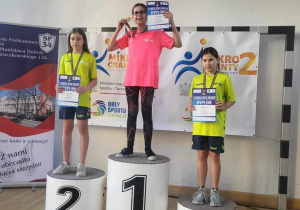 Uczniowie biorący udział w mistrzostwach stoja na podium podczas dekoracji medalami.