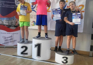 Uczniowie biorący udział w mistrzostwach stoja na podium podczas dekoracji medalami.