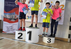 Uczniowie biorący udział w mistrzostwach stoja na podium podczas dekoracji medalami.