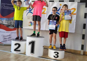 Uczniowie biorący udział w mistrzostwach stoja na podium podczas dekoracji medalami.