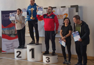 Pani Agnieszka stoi na podium trzymając w ręku puchar za zdobycie drugiego miejsca.