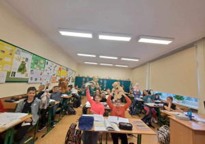 Uczniowie z klasy 6b siedzą w ławkach i prezentują swoje Misie.