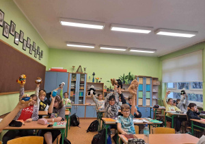 Uczniowie z klasy 5a siedzą w klasie i prezentują swoje Misie.