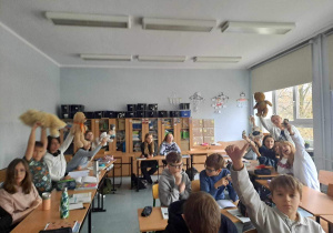 Uczniowie z klasy 8a siedzą w klasie i prezentują swoje Misie.