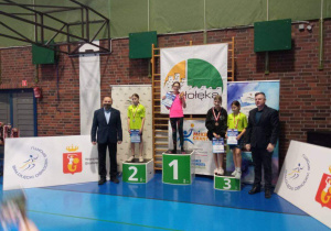 Uczniowie stoją na podium podczas dekoracji medalami.