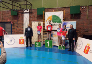 Uczniowie stoją na podium podczas dekoracji medalami.