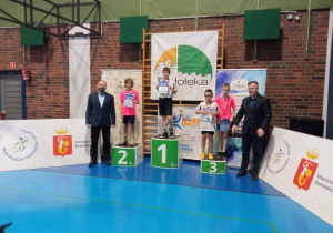 Uczniowie stoją na podium podczas dekoracji medalami.