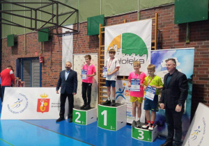 Uczniowie stoją na podium podczas dekoracji medalami.
