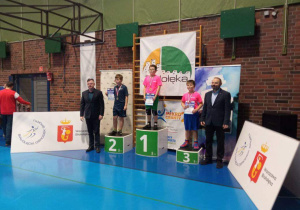 Uczniowie stoją na podium podczas dekoracji medalami.