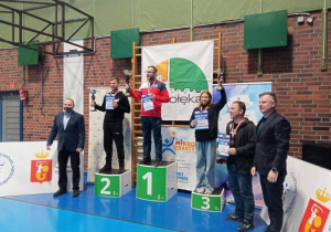 Nauczyciele i uczennica naszej szkoły stoją na podium podczas dekoracji medalami.