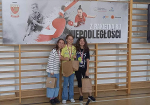 Dziwczynki z medalami i uśmiechami na buziach stoją przy drabinkach.