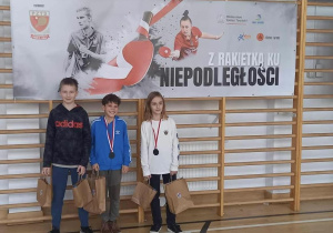 Chłopcy z medalami i uśmiechami na buziach stoją przy drabinkach.