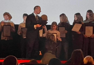 Pan Aleksander Ferens wręcza dyplomy nagrodzonym uczniom.