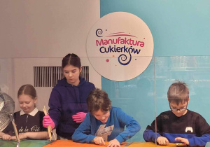 Sofiia, Kasia, matt i Kacper samodzielnie skręcają swoje lizaki na patyki.