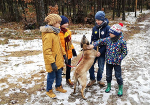 Uczniowie z psem podczas spaceru w lesie.