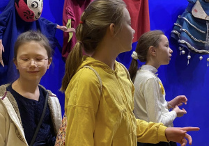 Uczniowie czekając na spektakl ogladaja wystawę teatralnych lalek.