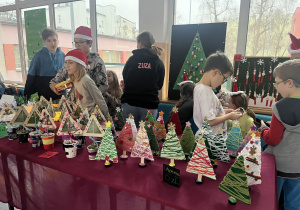 Uczniowie sprzedają na kiermaszu ozdobne choinki.