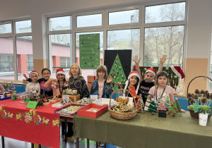 Mikołajki pomagają w sprzedaży ozdób świątecznych na kiermaszu.