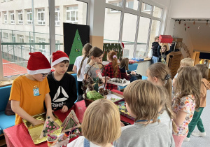 Uczniowie z klas trzecich pomagają w sprzedazy ozdób świątecznych.