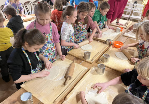Uczniowie wałkują ciasto na pierogi.