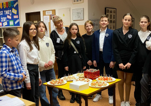 Starsi uczniowie razem z nauczycielami witają gości. Na stoliku czeka poczęstunek dla rodziców i dzieci.