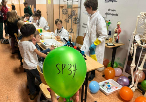 Starsi uczniowie pokazują młoszym kolegom chemiczne eksperymenty.