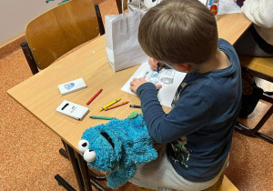 Przyszły uczeń koloruje torebkę papierową.