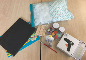 Różnorodne materiały do wykonania pracy (kartki białe i czarne, białe piórka, patyczki drewniane, klej magiczny, papier do origami - kółka, pestki słonecznika).