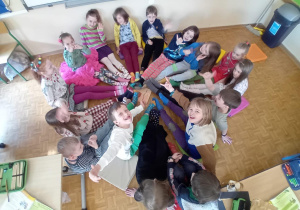 Dzieci siedzą w kółku z wyciągniętymi nóżkami i prezentują swoje kolorowe skarpetki.